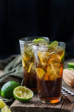 Gıda ve içecek, tatil partisi konsepti. Cuba libre veya long Island buzlu çay alkol kokteyl içki içecek, saman, buz ve kireç karanlık bir tablo ile bir bardak DRINK