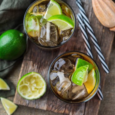 Gıda ve içecek, tatil partisi konsepti. Cuba libre veya long Island buzlu çay alkol kokteyl içki içecek, saman, buz ve kireç karanlık bir tablo ile bir bardak DRINK. Üstten görünüm düz yatıyordu