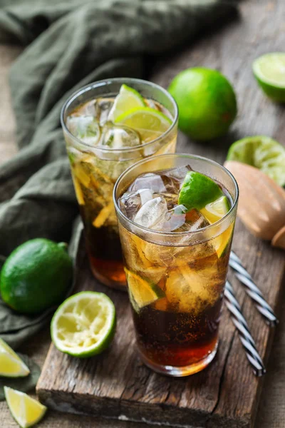 Food and drink, holidays party concept. Cuba libre or long island iced tea alcohol cocktail drink beverage, longdrink in a glass with straw, ice and lime on a dark table