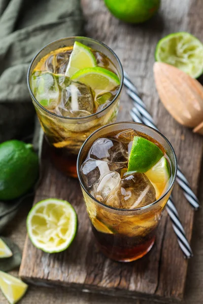 Food and drink, holidays party concept. Cuba libre or long island iced tea alcohol cocktail drink beverage, longdrink in a glass with straw, ice and lime on a dark table