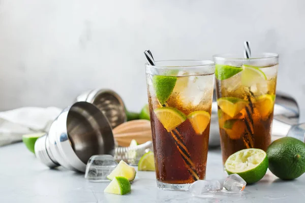 Food and drink, holidays party concept. Cuba libre or long island iced tea alcohol cocktail drink beverage, longdrink in a glass with straw, ice and lime on a table