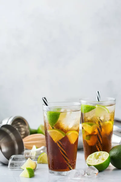 Food and drink, holidays party concept. Cuba libre or long island iced tea alcohol cocktail drink beverage, longdrink in a glass with straw, ice and lime on a table. Copy space background