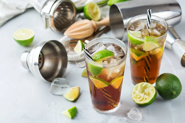 Food and drink, holidays party concept. Cuba libre or long island iced tea alcohol cocktail drink beverage, longdrink in a glass with straw, ice and lime on a table