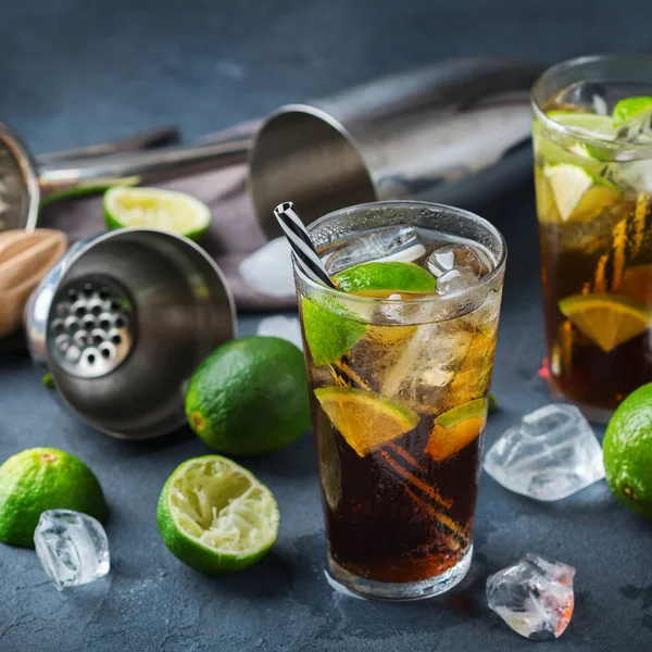 Food and drink, holidays party concept. Cuba libre or long island iced tea alcohol cocktail drink beverage, longdrink in a glass with straw, ice and lime on a dark table