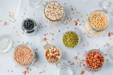 Sağlıklı gıda, diyet, beslenme kavramı, vegan protein kaynağı. Kavanoz, mercimek, soya fasulye, nohut modern mutfak masasında içinde renkli baklagiller ürün yelpazesine. Üst görüntülemek düz yatıyordu arka plan