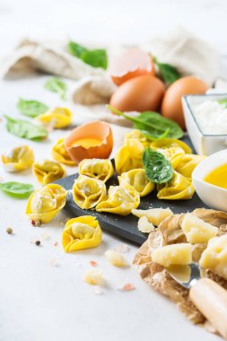İtalyan gıda ve malzemeler, el yapımı tortellini yeşil ıspanak ve ricotta peynirli bir mutfak masasında bir kesme tahtası üzerinde ürün yelpazesine