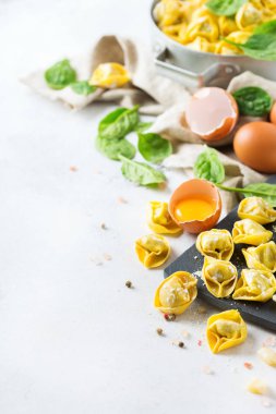İtalyan gıda ve malzemeler, el yapımı tortellini yeşil ıspanak ve ricotta peynirli bir mutfak masasında bir kesme tahtası üzerinde ürün yelpazesine. Alan arka plan kopyalama