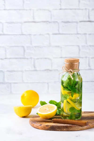 Health care, fitness, healthy nutrition diet concept. Fresh cool lemon lime mint infused water, cocktail, detox drink, lemonade in a glass jar for spring summer days. Light copy space background
