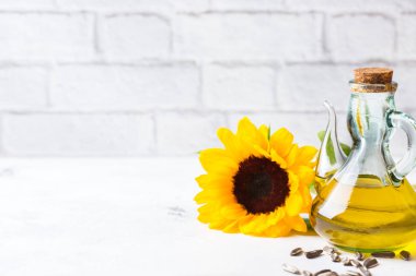 Gıda diyet ve beslenme kavramı. Taze organik sızma ayçiçek yağı şişeleri çiçeklerle beyaz mutfak masası üzerinde ürün yelpazesine. Alan arka plan kopyalama