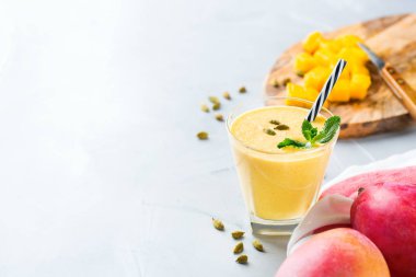 Sağlıklı organik mango lassi, güler yüzlü, sallamak, Hint içki içecek yoğurt ve mutfak masasının üzerinde taze olgunlaşmış meyve ile. Alan arka plan kopyalama