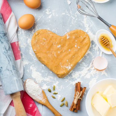 Pişirme malzemeleri ve kalp ile mutfak eşyaları pişirme hamur Sevgililer günü için bir mutfak masasında şeklinde. Un, şeker, tereyağı, yumurta, baharat, tatlım. En iyi görünüm düz yatıyordu kopya alan arka plan