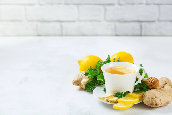 Food and drink, still life health care concept. Ginger tea infusion beverage in white cup with lemon mint honey on a kitchen table for cold and flu winter autumn days. Copy space background