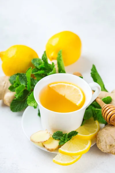 Food and drink, still life health care concept. Ginger tea infusion beverage in white cup with lemon mint honey on a kitchen table for cold and flu winter autumn days