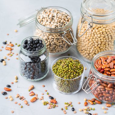 Sağlıklı gıda, diyet, beslenme kavramı, vegan protein kaynağı. Kavanoz, mercimek, soya fasulye, nohut modern mutfak masasında içinde renkli Bakliyat Çeşitleri