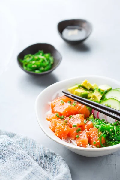 Hızlı ve sağlıklı yemek, yemek, beslenme kavramı. Kase taze organik hawaiian somon poke pirinç, deniz yosunu, avokado, salatalığın üzerinde modern mutfak masası