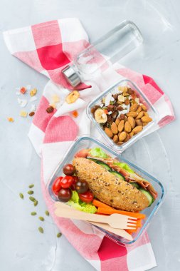 Food and drink, still life, diet and nutrition, healthy eating, take away concept. Lunch box with sandwich, fruits, vegetables, nut mix and bottle of water. Top view flat lay background clipart