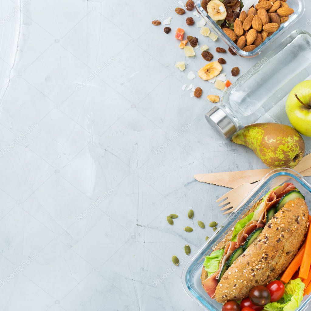 Food and drink, still life, diet and nutrition, healthy eating, take away concept. Lunch box with sandwich, fruits, vegetables, nut mix and bottle of water. Top view flat lay, copy space background