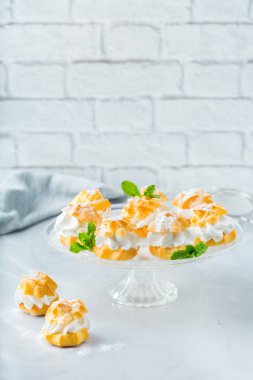 Yiyecek ve içecek, tatil kavramı. Modern mutfak masası üzerinde krema ile lezzetli tatlı ev yapımı profiterol. Alan arka plan kopyalama