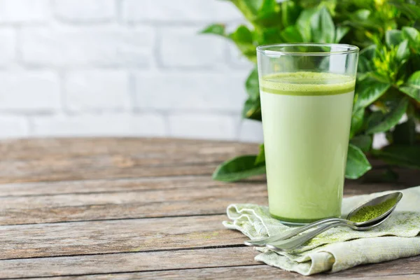 Vaso de té verde matcha con leche sobre una mesa de madera — Foto de Stock