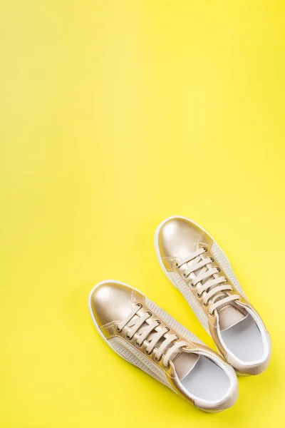 Pair of golden female sneakers on yellow background — Stock Photo, Image