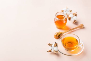 Pastel pembe, kayısı arka plan üzerinde bal ile çay Fincan