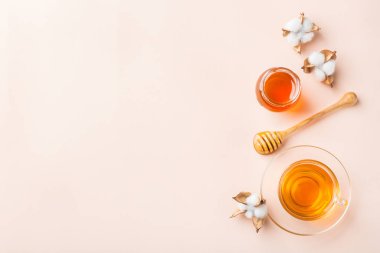 Pastel pembe, kayısı arka plan üzerinde bal ile çay Fincan