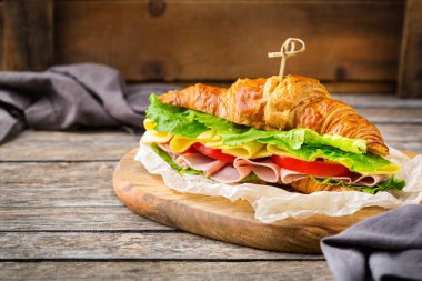 Jambon, peynir, marul ve domatesli taze kruvasan sandviçi.