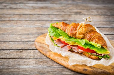 Jambon, peynir, marul ve domatesli taze kruvasan sandviçi.