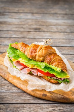 Jambon, peynir, marul ve domatesli taze kruvasan sandviçi.