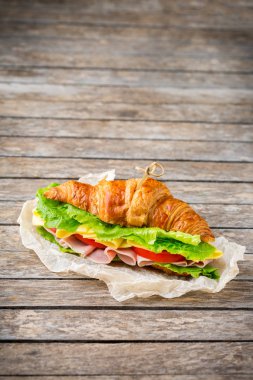 Jambon, peynir, marul ve domatesli taze kruvasan sandviçi.
