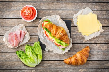 Jambon, peynir, marul ve domatesli taze kruvasan sandviçi.