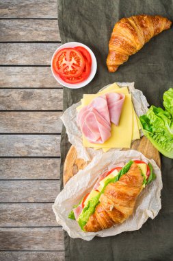 Jambon, peynir, marul ve domatesli taze kruvasan sandviçi.