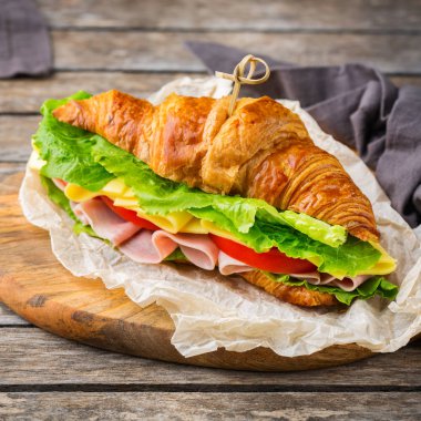 Jambon, peynir, marul ve domatesli taze kruvasan sandviçi.