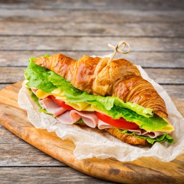 Jambon, peynir, marul ve domatesli taze kruvasan sandviçi.