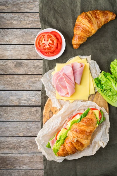 Fresh croissant sandwich with ham, cheese, lettuce and tomato