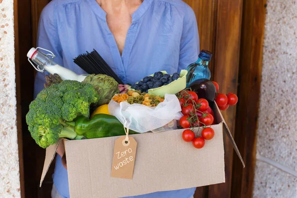 Zero waste no plastic home delivery service. Senior woman holding in hands box of food in recyclable and reusable, eco friendly package. Online internet order, shopping. Sustainable lifestyle concept
