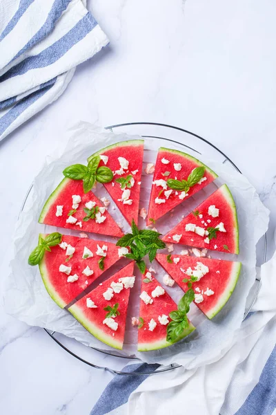 Healthy clean eating, dieting and nutrition, seasonal, summer concept. Watermelon pizza with feta cheese and herbs on a table. Top view flat lay copy space background.