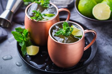 Klasik Moskova katır kokteyli. Yeşil kireç, nane şekeri, siyah bir masada bakır bardakta buz..