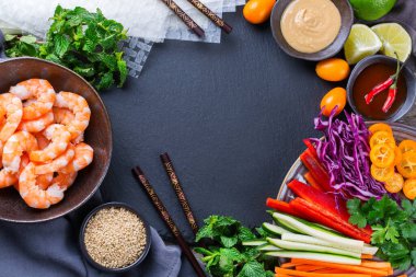 Pilav kağıdı, havuç, biber sosu, kırmızı lahana, kabak, biber, karides ve kumkat ile bahar veya yaz ruloları hazırlığı. Lezzetli Asya yemekleri. Üst görünüm düz arkaplan