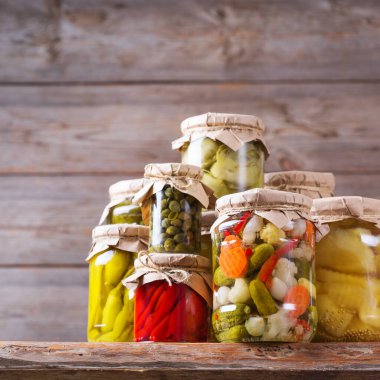 Korunmuş ve mayalanmış yiyecekler. Ahşap bir masada çeşitli salamura ve marine edilmiş sebzelerle ev yapımı kavanozlar. Oda temizliği, ev ekonomisi, hasat koruma  