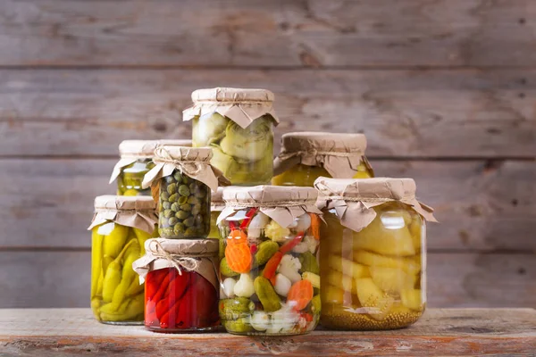 Preserved and fermented food. Assortment of homemade jars with variety of pickled and marinated vegetables on a wooden table. Housekeeping, home economics, harvest preservation