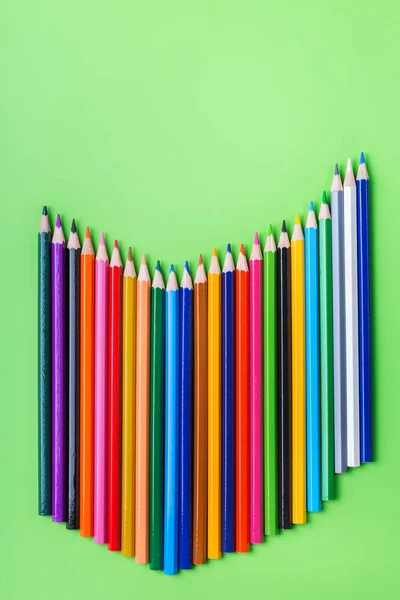 Oil pastel crayons lying on a paper with painted rainbow Stock