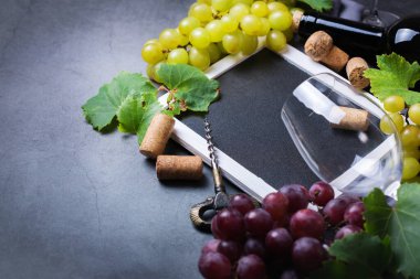 Yiyecek ve içecek, sonbahar hasat konsepti. Şarap tatma, içki içme, sembollü davetiye, üzüm asması, şişe, bardak, tirbuşon. Boşluk siyah arkaplanı kopyala