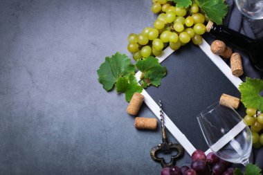 Yiyecek ve içecek, sonbahar hasat konsepti. Şarap tatma, içki içme, sembollü davetiye, üzüm asması, şişe, bardak, tirbuşon. Boşluk siyah arkaplanı kopyala