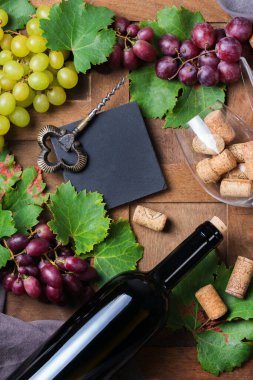 Yiyecek ve içecek, sonbahar hasat konsepti. Şarap tatma, içki içme, sembollü davetiye, üzüm asması, şişe, bardak, tirbuşon. Ahşap arkaplan