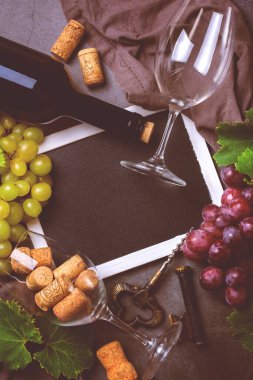 Yiyecek ve içecek, sonbahar hasat konsepti. Şarap tatma, içki içme, sembollü davetiye, üzüm asması, şişe, bardak, tirbuşon. Siyah arkaplan, tonlu