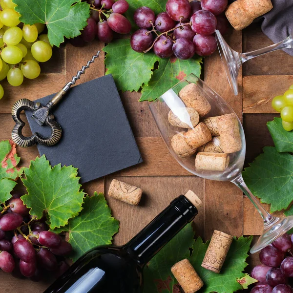 Food and drink, harvest autumn fall concept. Wine tasting, degustation, invitation card with symbols - grape vine, bottle, glasses, corkscrew. Wooden background