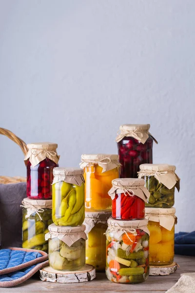 Preserved and fermented food. Assortment of homemade jars with variety of pickled and marinated vegetables, fruit compote on a wooden table. Housekeeping, home economics, harvest preservation