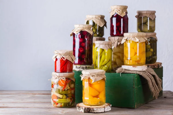 Preserved and fermented food. Assortment of homemade jars with variety of pickled and marinated vegetables, fruit compote on a wooden table. Housekeeping, home economics, harvest preservation