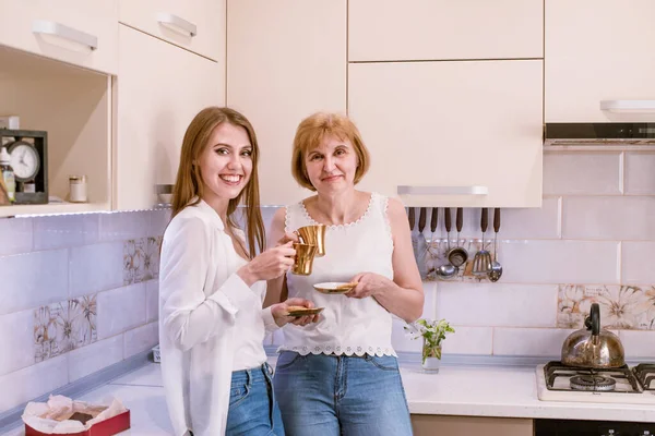 Las mujeres sostienen tazas de oro con café, té en las manos disfrutando de la conversación, mirando en la cámara —  Fotos de Stock